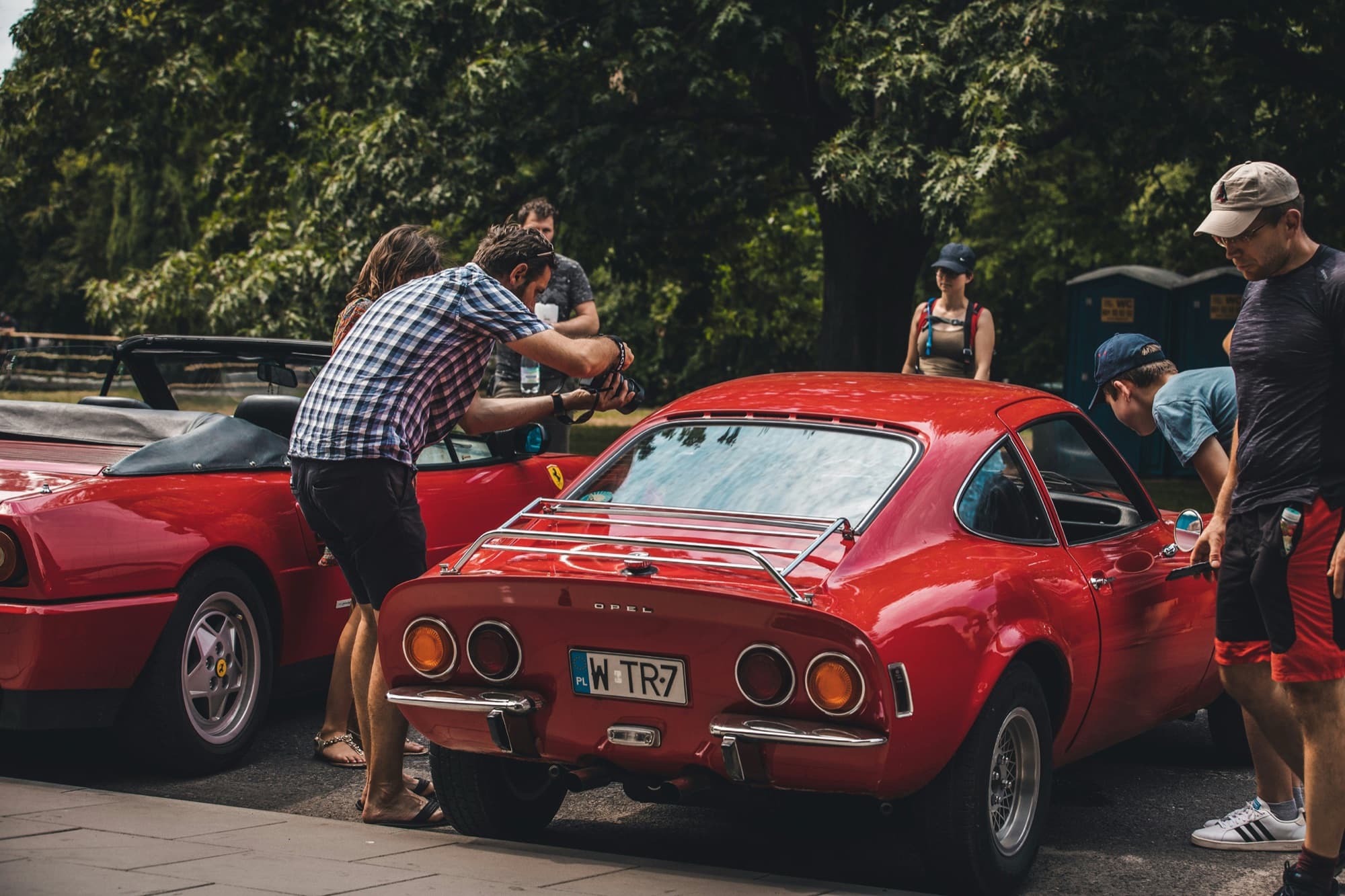 Crowd walking through rows of cars at an outdoor automotive event