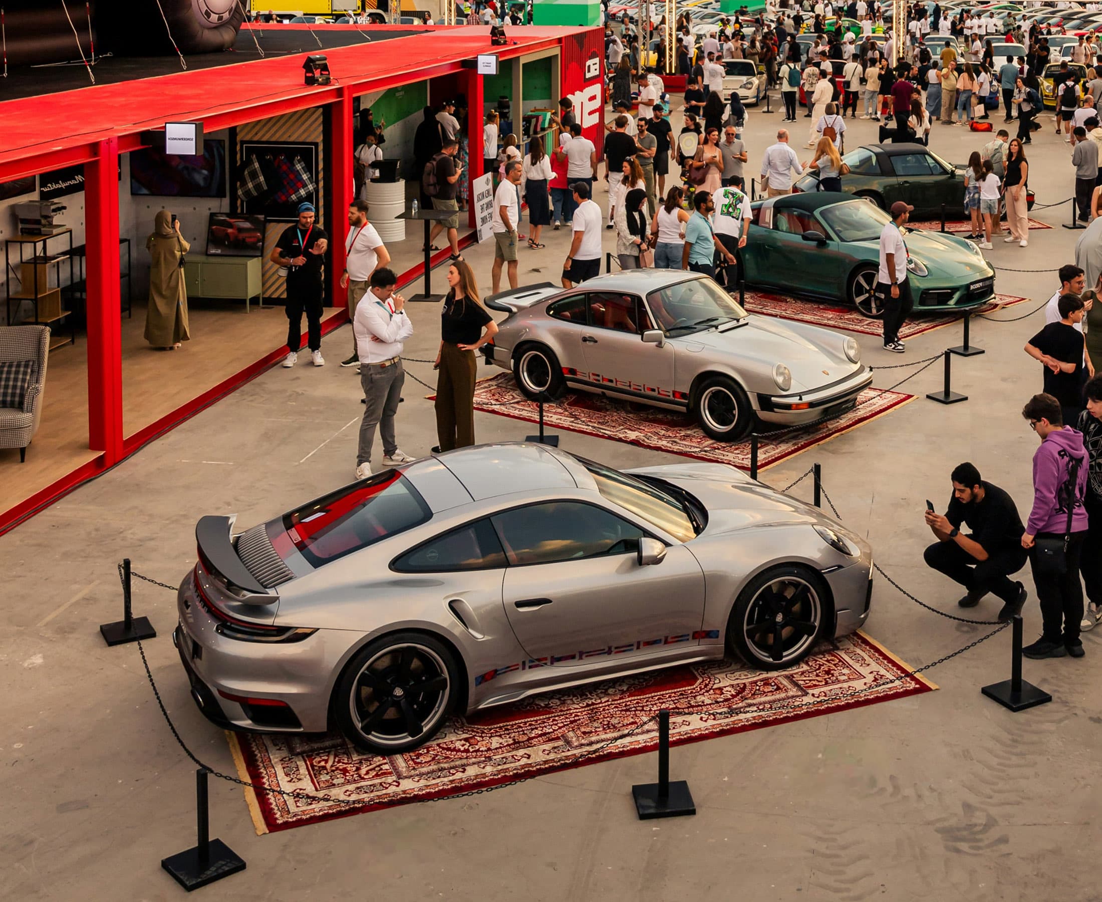 Crowd walking through rows of cars at an outdoor automotive event