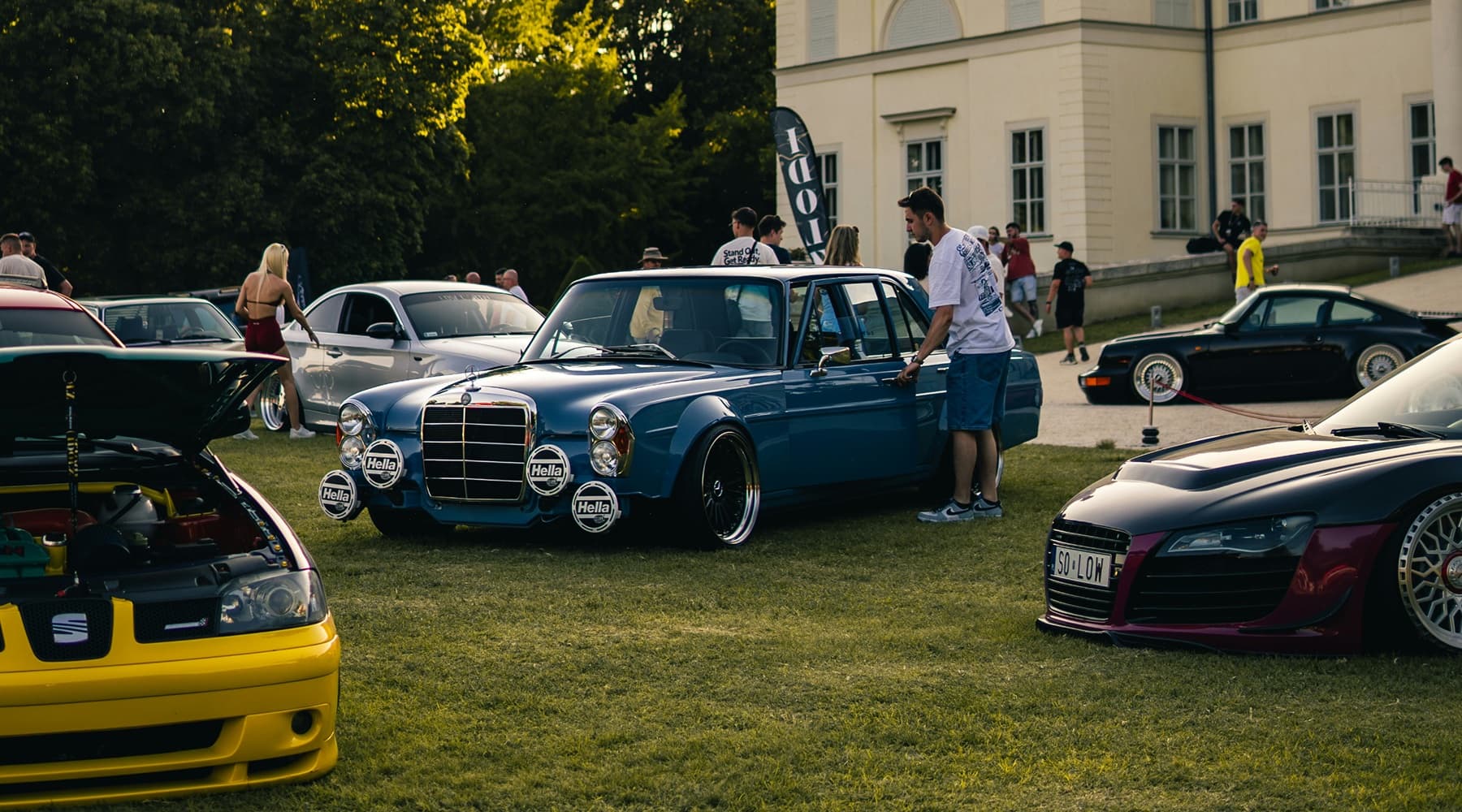 Cars lined up at an outdoor automotive event at sunset