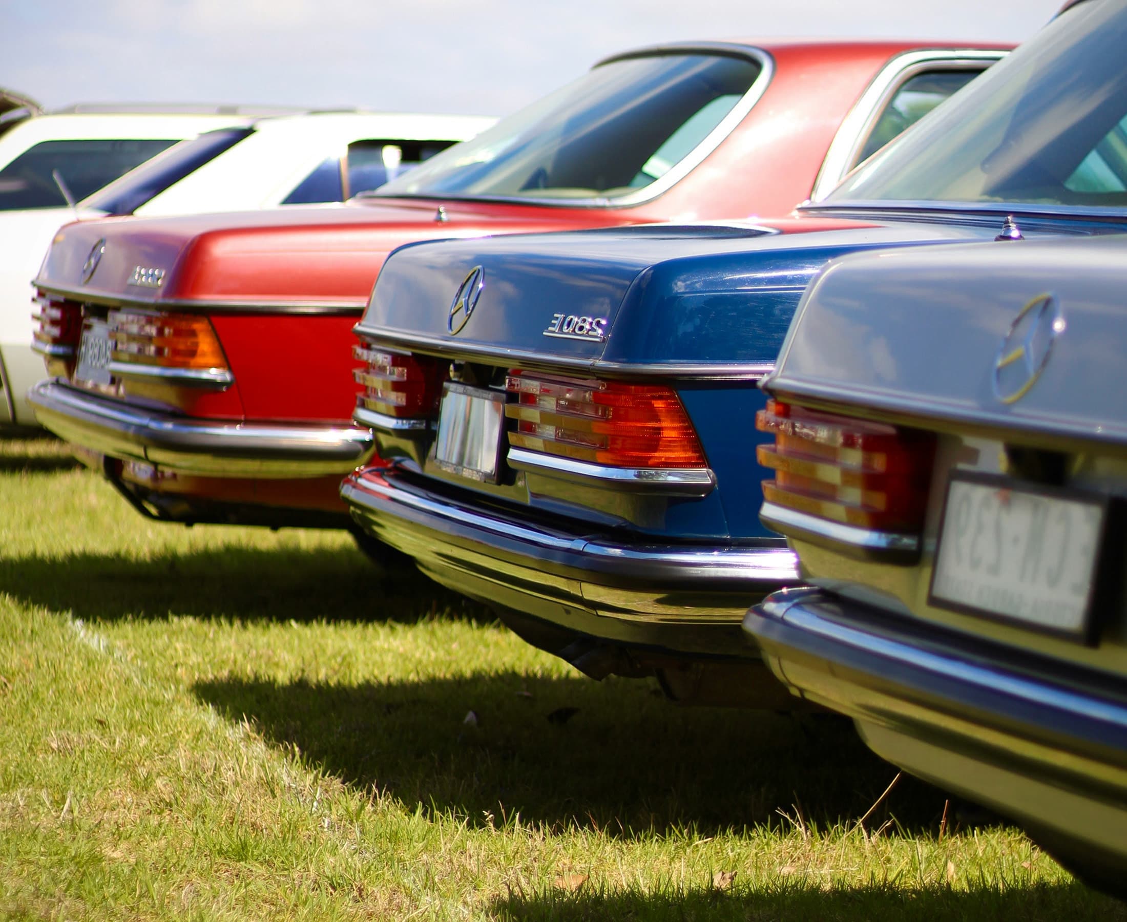 Cars lined up for on-site check-in at an outdoor automotive event
